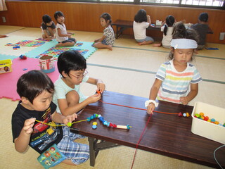 河東第三幼稚園のお友だちと一緒に紐通しをしているところ